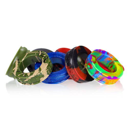 varios anillos para pene de colores diversos, militar, azul, rojo y negro, arco iris puesto en un pequeño monton sobre fondo blanco