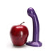 Dildo anal estimulador de prostata Tantus Sport morado al lado de una manzana sobre un fondo blanco